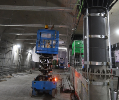 地铁昌平线南延现场,工人使用升降平台车安装站厅设备